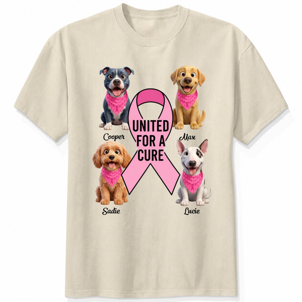 A sand short-sleeve crewneck t-shirt featuring a graphic print of dogs wearing pink bandanas around a large pink ribbon with the text 'UNITED FOR A CURE'.