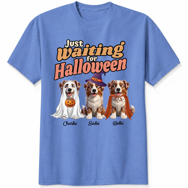 A blue short-sleeve crewneck t-shirt featuring dogs dressed in costumes and the text 'Just Waiting for Halloween'.
